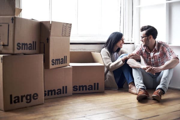 Couple sitting on the floor of a new apartment surrounded by Small Haul moving boxes